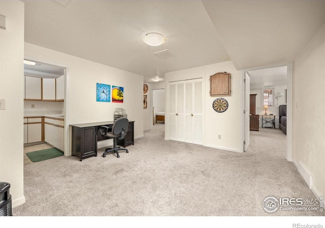 carpeted office space featuring baseboards and visible vents