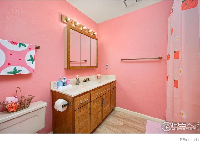 full bathroom featuring vanity, toilet, baseboards, and wood finished floors