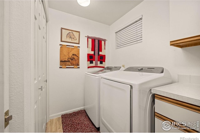 washroom with cabinet space, independent washer and dryer, and baseboards