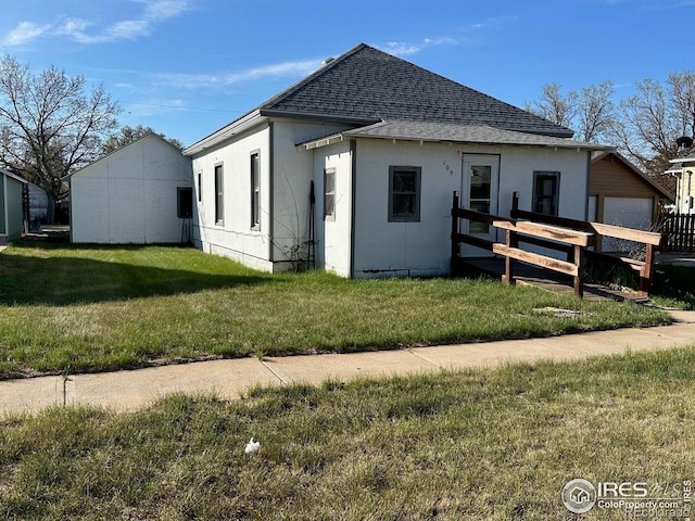 109 E 5th St, Julesburg, CO 80737 - rear view of property with a yard, stucco siding, and roof with shingles