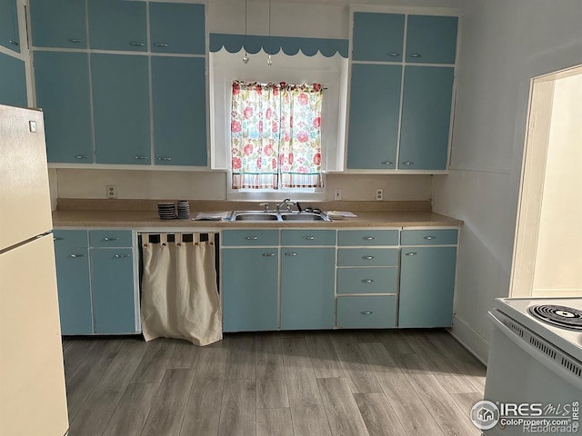 109 E 5th St, Julesburg, CO 80737 - kitchen featuring white appliances, light countertops, light wood-type flooring, and a sink