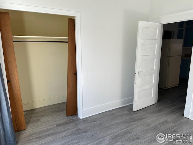 109 E 5th St, Julesburg, CO 80737 - unfurnished bedroom with freestanding refrigerator, a closet, wood finished floors, and baseboards