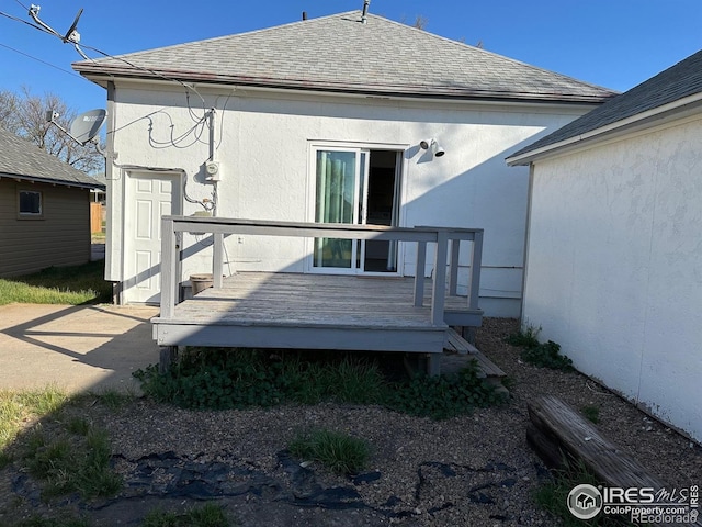 109 E 5th St, Julesburg, CO 80737 - back of house featuring roof with shingles, a deck, and stucco siding