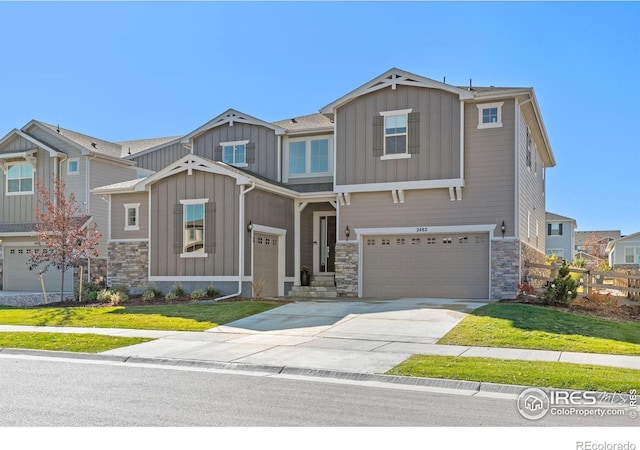 craftsman-style home with board and batten siding, stone siding, a garage, driveway, and a front lawn