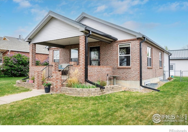 bungalow with a porch, brick siding, a front lawn, and fence