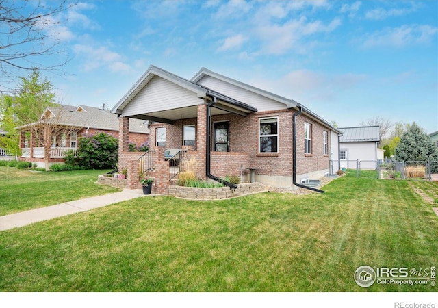 view of front of home with covered porch, fence, a front lawn, and brick siding