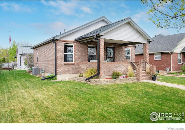 view of front facade with central AC unit, covered porch, brick siding, and a front yard