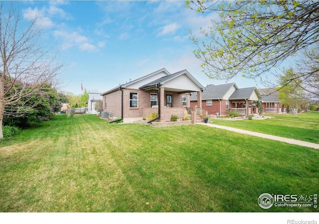 view of front of property with cooling unit, brick siding, a front yard, and a porch