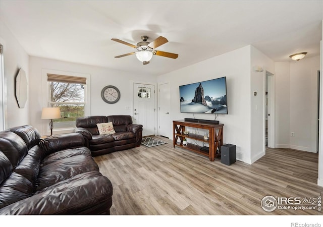 living room featuring baseboards, a ceiling fan, and light wood-style floors