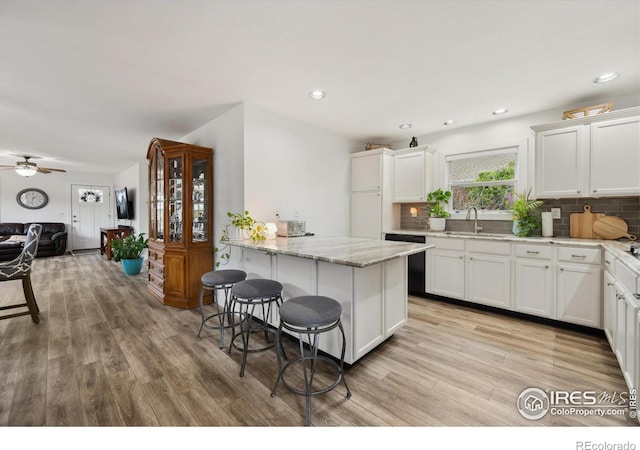 kitchen featuring a sink, tasteful backsplash, a kitchen bar, and light wood-style floors