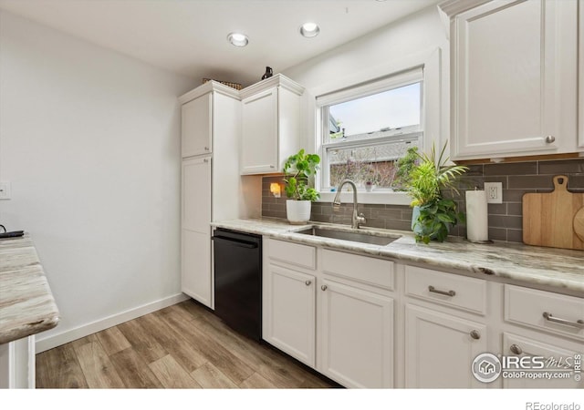 kitchen with dishwasher, light wood finished floors, a sink, white cabinetry, and decorative backsplash