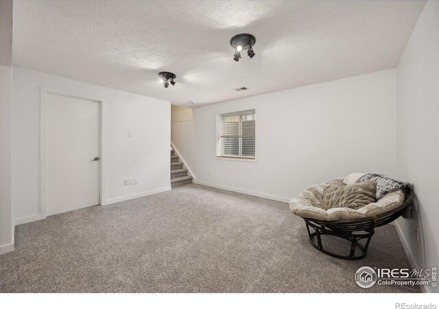 living area featuring stairs, a textured ceiling, visible vents, carpet flooring, and baseboards