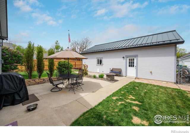 back of house featuring a lawn, a standing seam roof, fence, metal roof, and a patio area