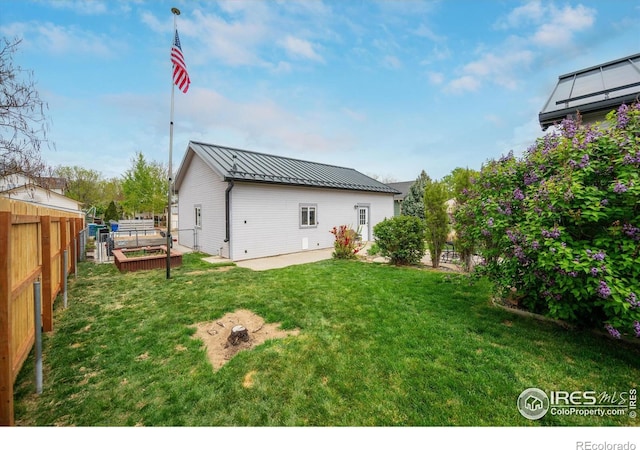 rear view of house with a yard, fence, metal roof, and a standing seam roof