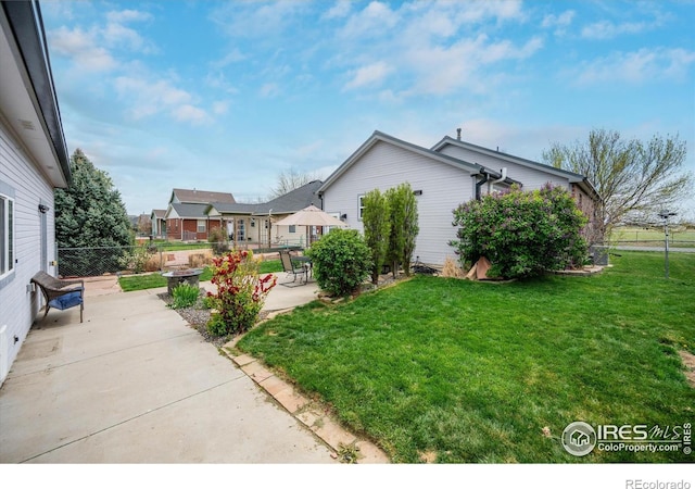 view of property exterior featuring a yard, a patio area, and fence