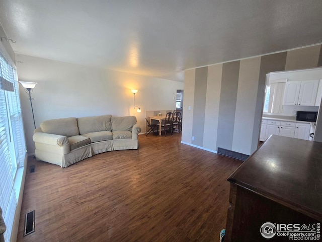 living room with visible vents, baseboards, and dark wood-type flooring