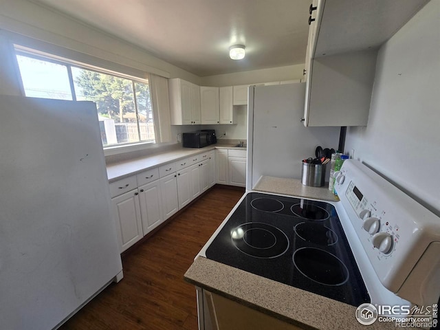 kitchen featuring white cabinets, light countertops, dark wood-style flooring, and white appliances
