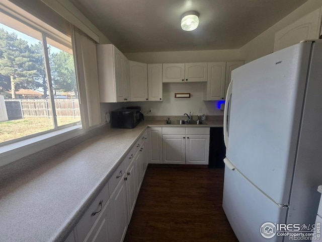 kitchen featuring freestanding refrigerator, white cabinetry, plenty of natural light, and a sink