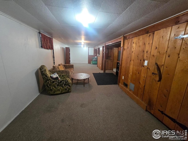 finished below grade area featuring carpet, wooden walls, baseboards, and visible vents