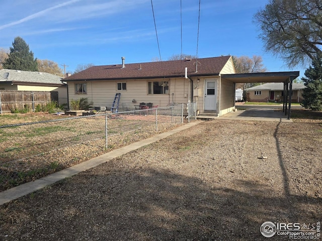 rear view of property featuring driveway, fence, and an attached carport