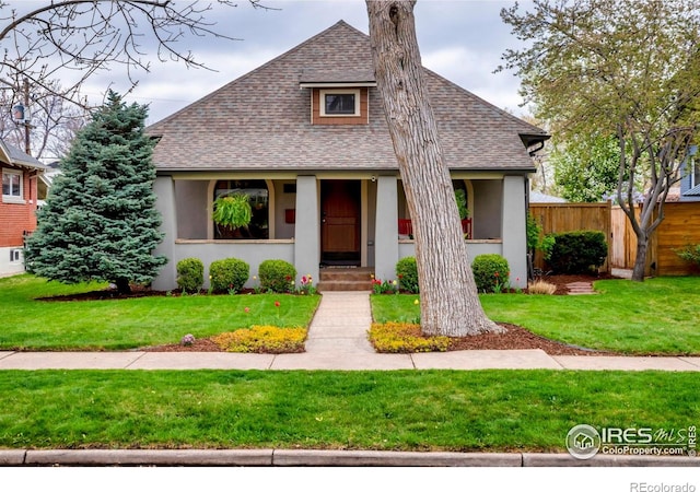 view of front of house with roof with shingles, fence, and stucco siding