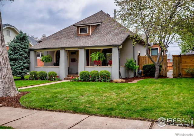 bungalow-style home featuring stucco siding, roof with shingles, a front lawn, and fence