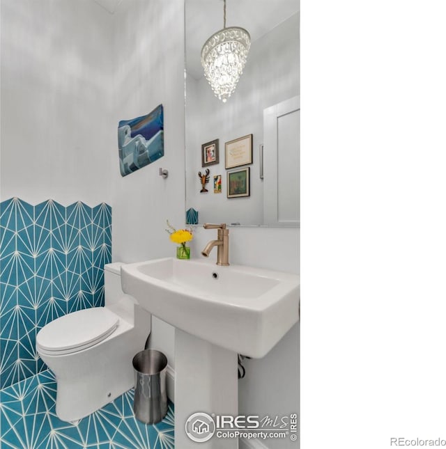 bathroom with toilet and a chandelier