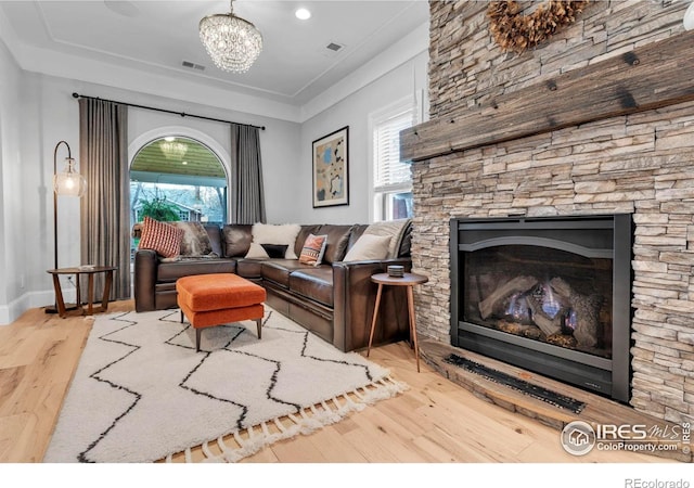 living area with an inviting chandelier, visible vents, plenty of natural light, and wood finished floors