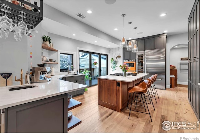 kitchen with open shelves, visible vents, recessed lighting, arched walkways, and appliances with stainless steel finishes