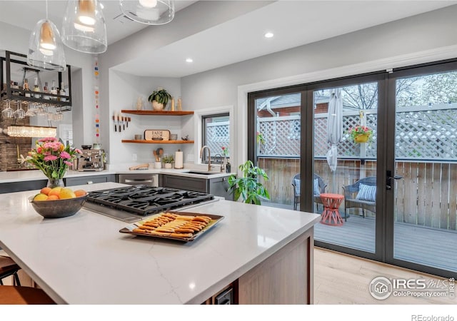 kitchen with plenty of natural light, cooktop, light wood-style flooring, and a sink