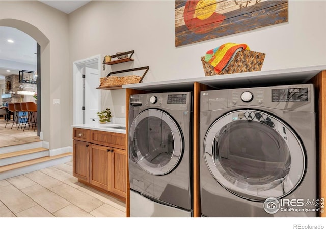 clothes washing area with cabinet space, recessed lighting, washing machine and clothes dryer, arched walkways, and light tile patterned floors