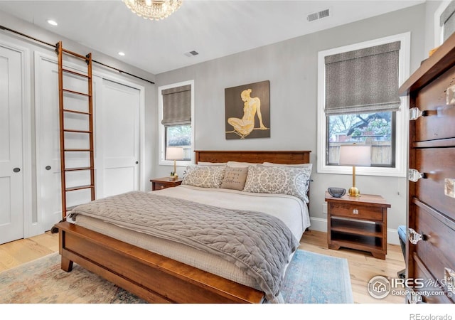 bedroom with multiple windows, light wood-type flooring, and visible vents