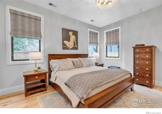 bedroom with baseboards, multiple windows, visible vents, and wood finished floors