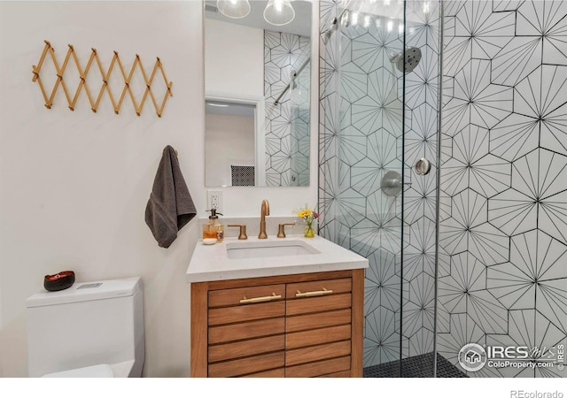 full bath featuring vanity, toilet, and tiled shower