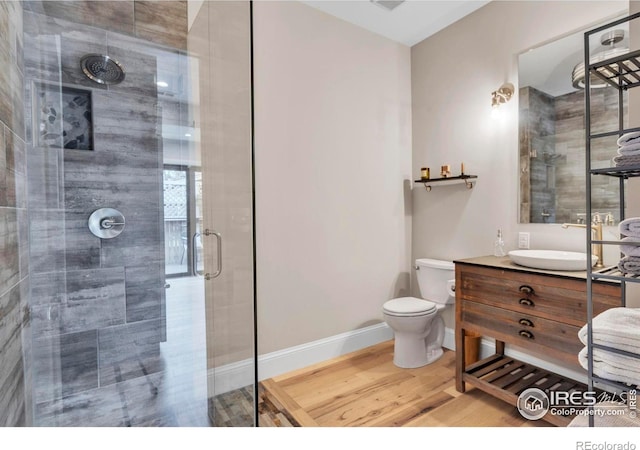 bathroom featuring a stall shower, baseboards, toilet, vanity, and wood finished floors