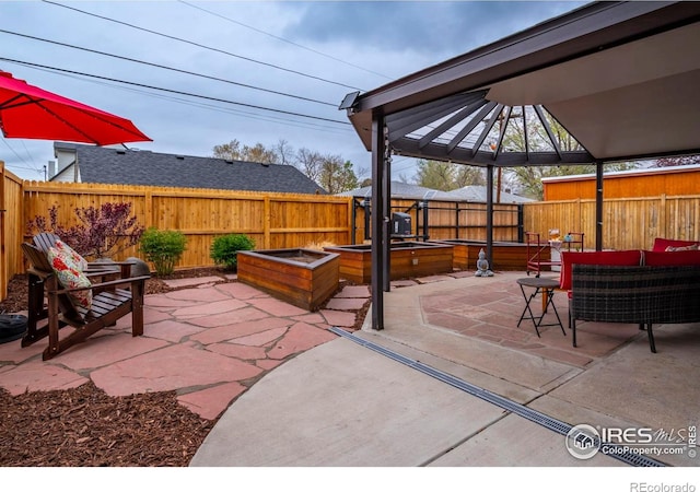 view of patio / terrace featuring a fenced backyard, a gazebo, an outdoor living space, and a garden