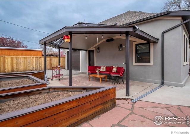 rear view of property featuring outdoor lounge area, fence, a patio, stucco siding, and a garden