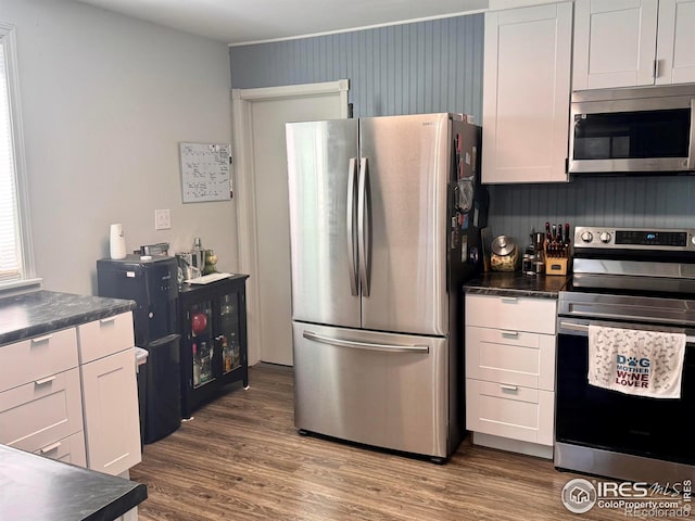 618 Melody Ln, Sterling, CO 80751 - kitchen with white cabinets, dark countertops, stainless steel appliances, and wood finished floors