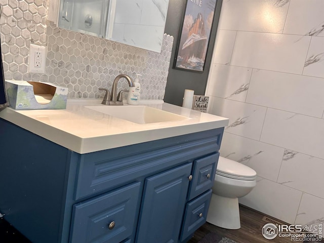 618 Melody Ln, Sterling, CO 80751 - bathroom with toilet, tile walls, wood finished floors, vanity, and backsplash
