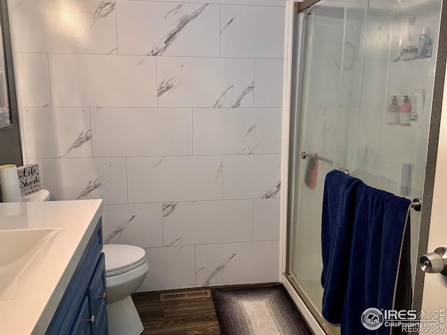 618 Melody Ln, Sterling, CO 80751 - full bathroom with toilet, tile walls, vanity, visible vents, and a shower stall