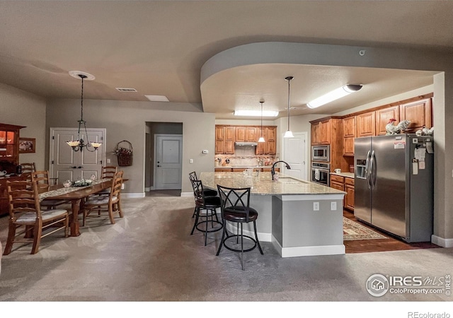 1379 Charles Dr Unit 4, Longmont, CO 80503 - kitchen featuring brown cabinetry, visible vents, a sink, stainless steel appliances, and an island with sink