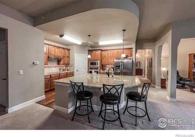 1379 Charles Dr Unit 4, Longmont, CO 80503 - kitchen with stainless steel appliances, a large island with sink, a kitchen breakfast bar, arched walkways, and baseboards