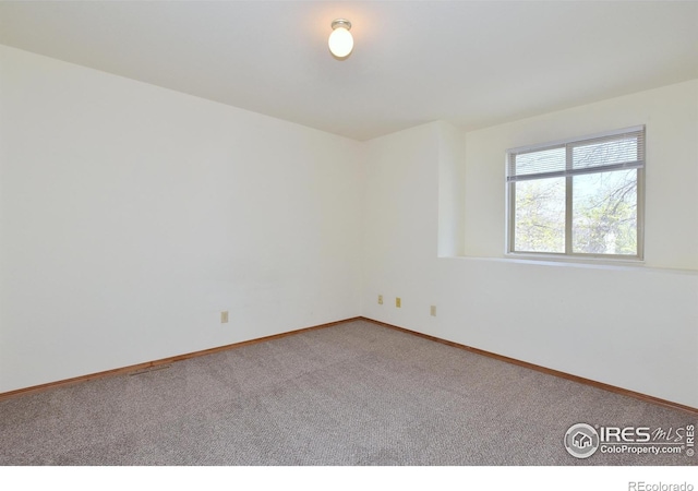 spare room featuring carpet and baseboards