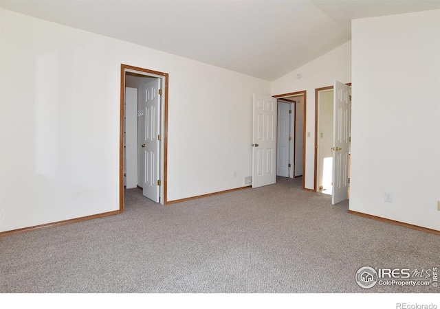 empty room with vaulted ceiling, carpet flooring, and baseboards