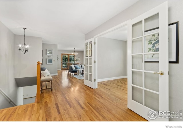 interior space with an inviting chandelier, baseboards, french doors, and wood finished floors