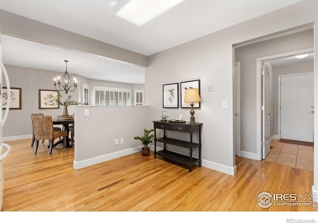 interior space featuring light wood-type flooring, a chandelier, and baseboards
