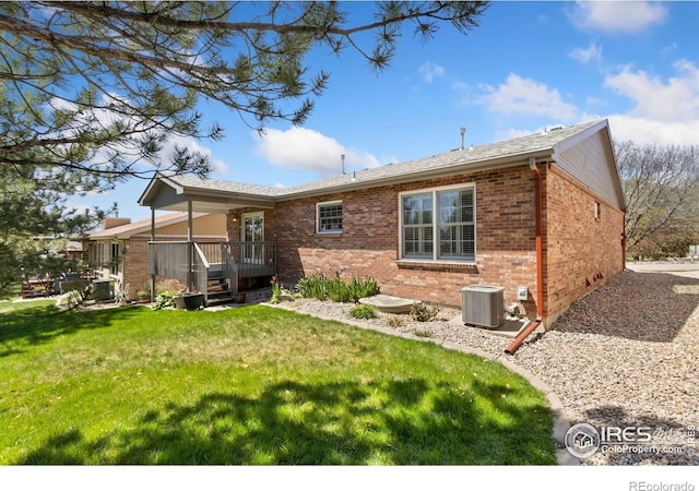back of house featuring cooling unit, brick siding, and a lawn