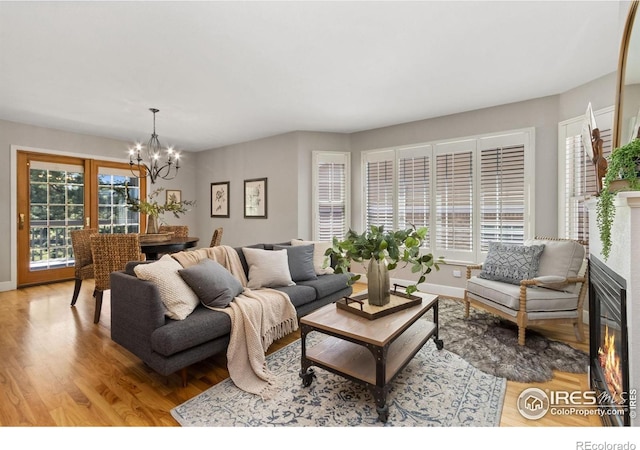 living area featuring baseboards, a notable chandelier, and light wood-style flooring