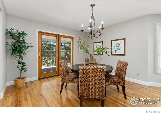 dining room with light wood finished floors, a chandelier, and baseboards