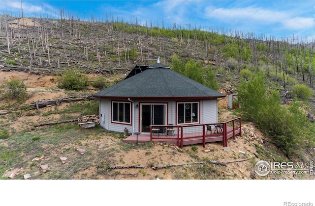 back of house featuring a shingled roof and a deck
